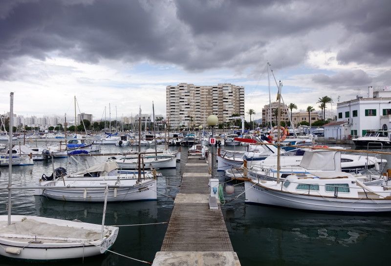 dunkle Wolken über weißen Booten im Hafen von Portixol