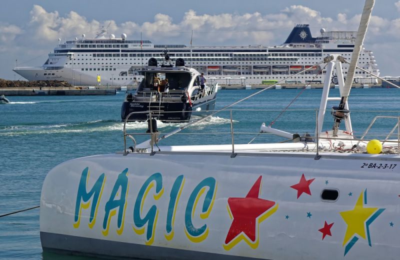 Yacht faehrt aus dem Hafen Kreutzfahrtschiff im Hintergrund